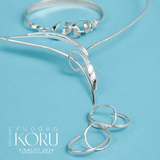 Close up of silver jewelry pieces on a turquoise background.