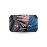 GULDVIVA gift card held by a hand in a blue sweater against a tree bark background.