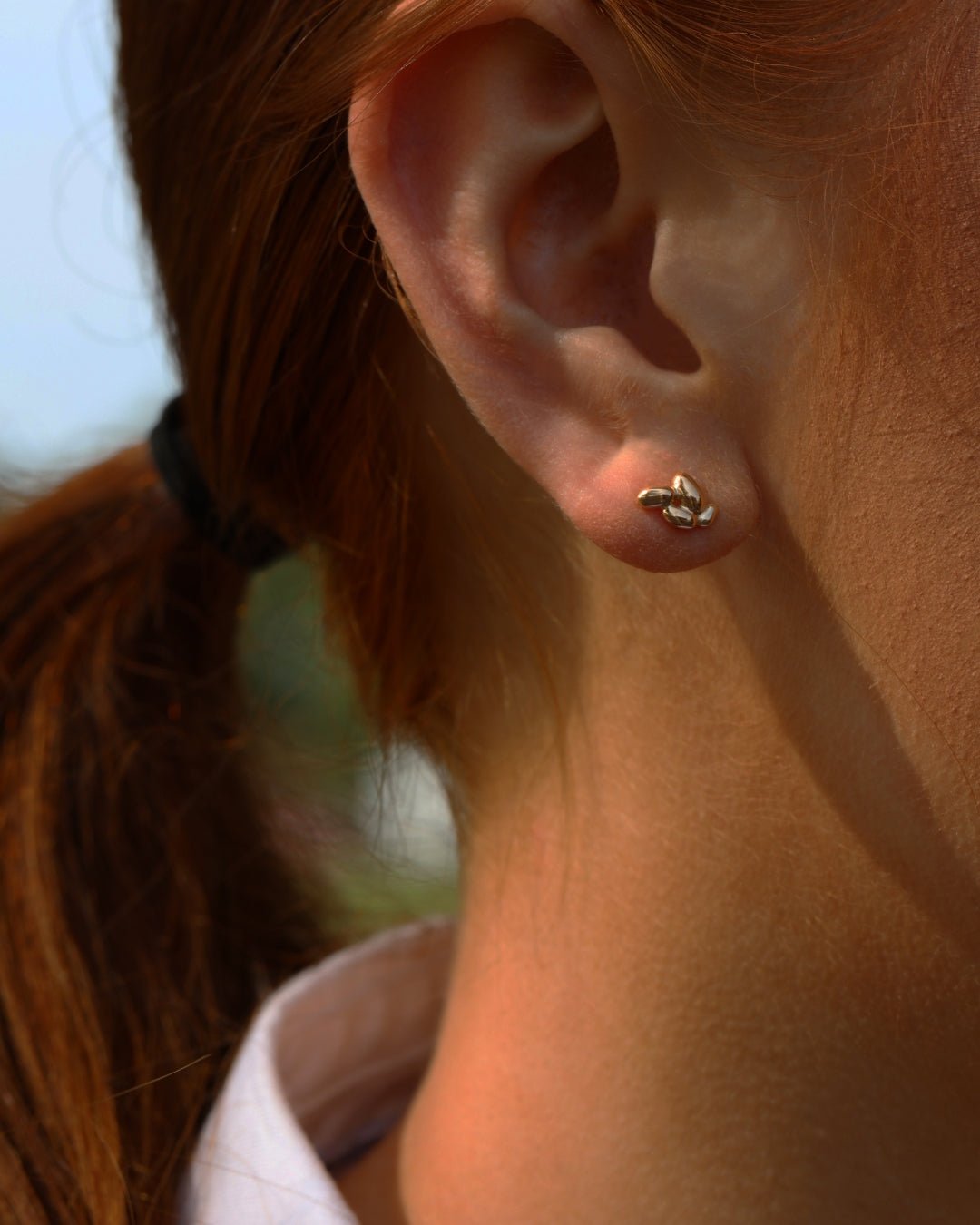 Close up of a small gold potato themed stud earring worn on the earlobe